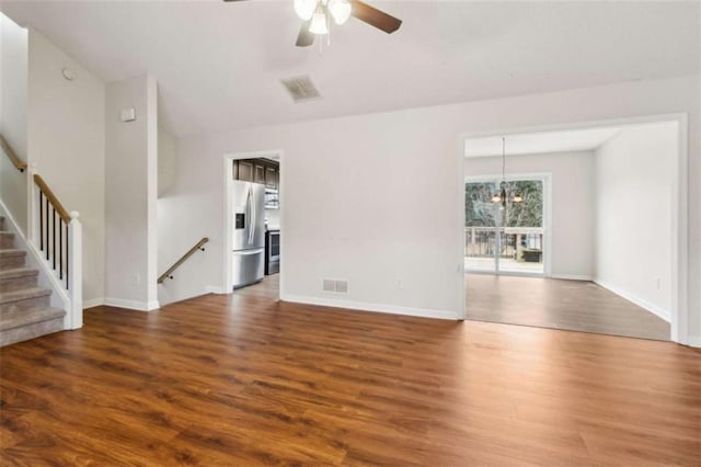 unfurnished living room featuring ceiling fan with notable chandelier and dark hardwood / wood-style floors