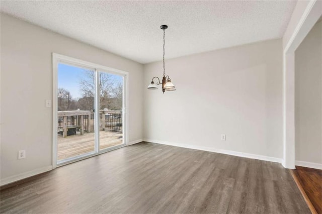 unfurnished dining area with a textured ceiling, dark hardwood / wood-style flooring, and a chandelier