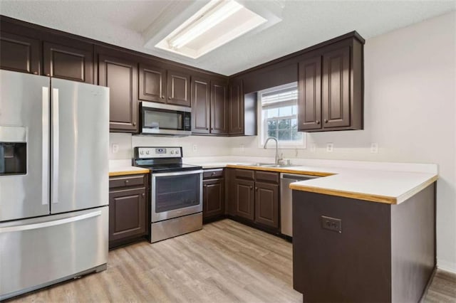 kitchen featuring sink, dark brown cabinets, light hardwood / wood-style flooring, and appliances with stainless steel finishes