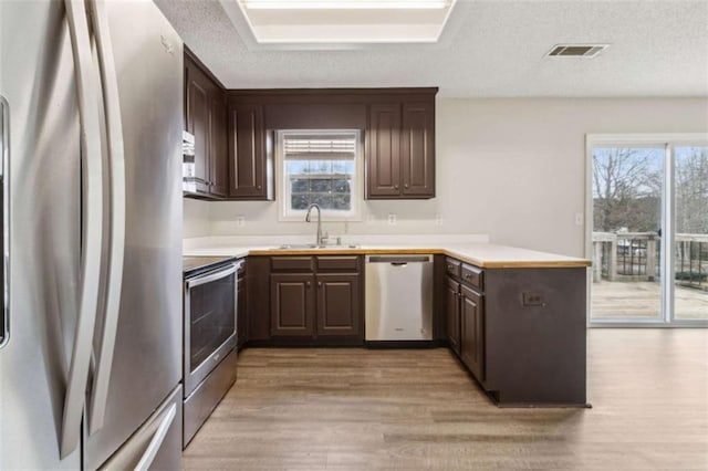 kitchen featuring plenty of natural light, sink, kitchen peninsula, and stainless steel appliances