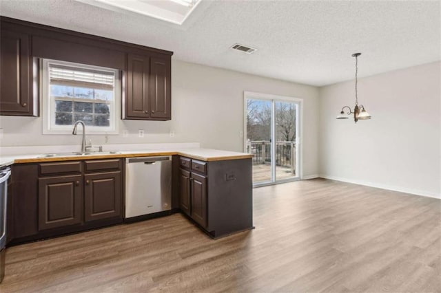 kitchen featuring kitchen peninsula, stainless steel dishwasher, hanging light fixtures, sink, and light wood-type flooring