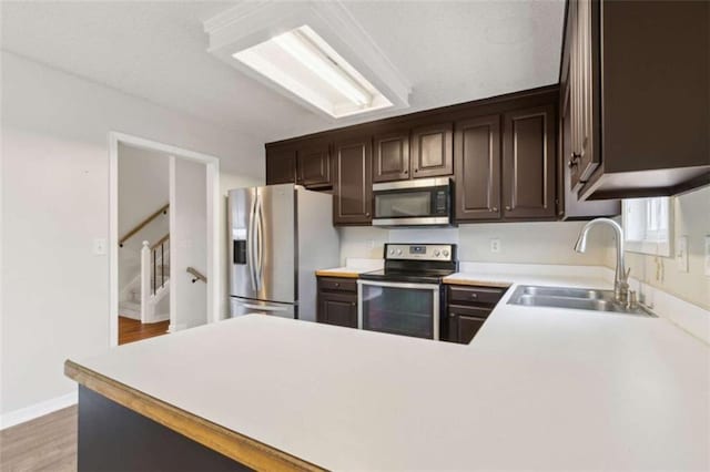 kitchen featuring sink, dark brown cabinets, light hardwood / wood-style flooring, and appliances with stainless steel finishes