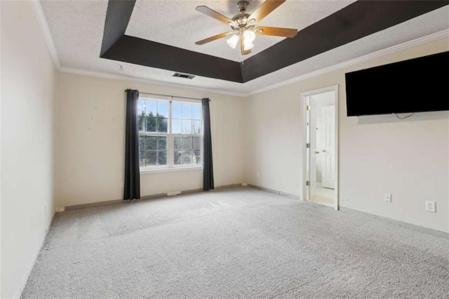 carpeted empty room featuring ceiling fan, a raised ceiling, crown molding, and a textured ceiling