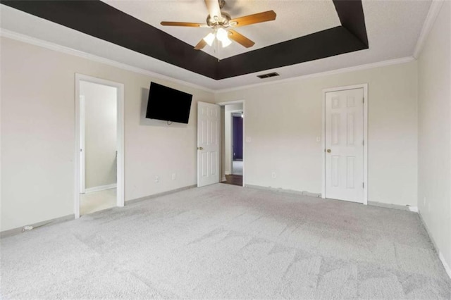 unfurnished room with ceiling fan, a raised ceiling, crown molding, and carpet floors