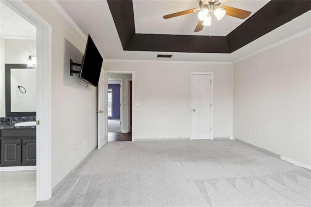 spare room with crown molding, ceiling fan, light carpet, and a raised ceiling