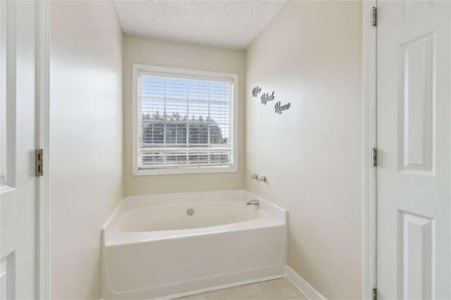 bathroom with a textured ceiling and a tub to relax in