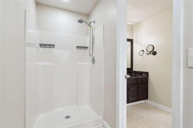 bathroom featuring a textured ceiling, walk in shower, and vanity