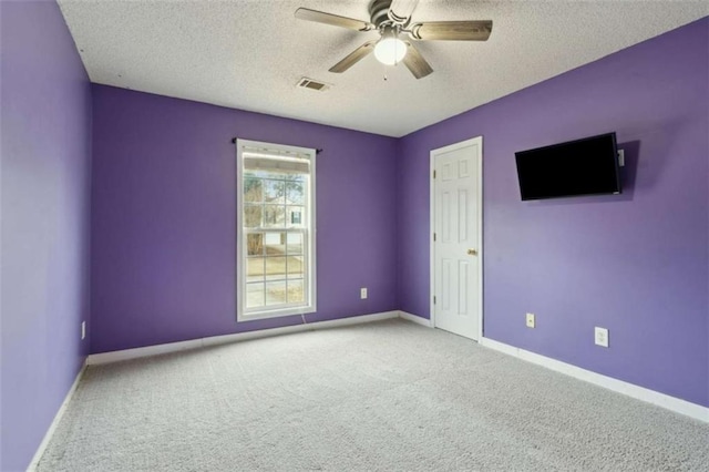 carpeted spare room featuring ceiling fan and a textured ceiling