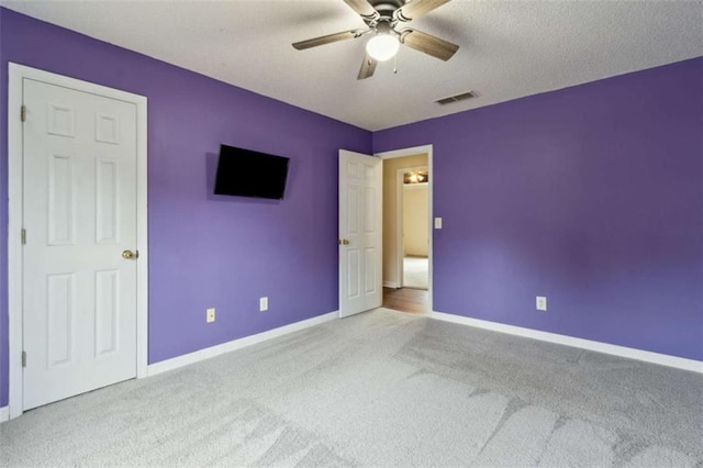 unfurnished bedroom featuring ceiling fan, a textured ceiling, and light carpet