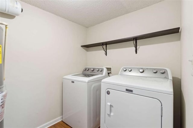 laundry area with a textured ceiling, washer and clothes dryer, and light wood-type flooring