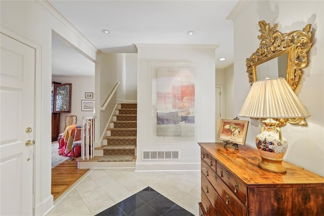 tiled entrance foyer featuring crown molding