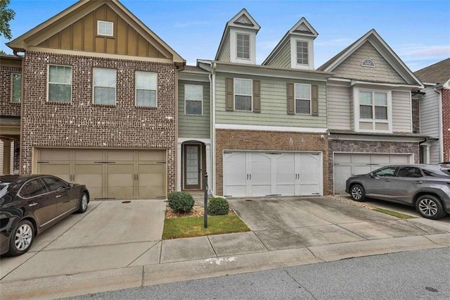 multi unit property featuring a garage, brick siding, board and batten siding, and driveway