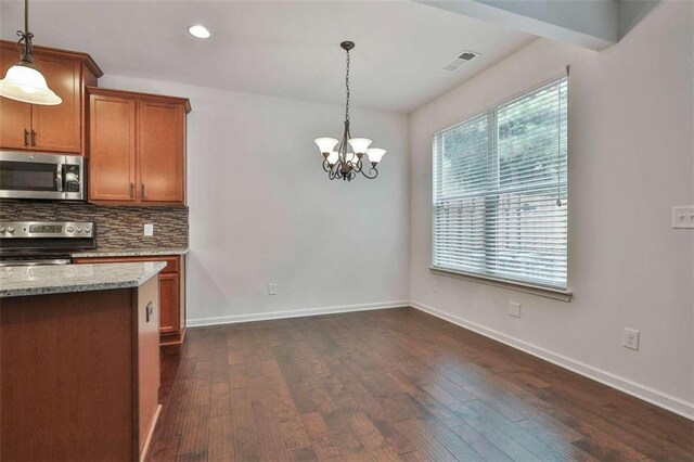 kitchen with dark wood-type flooring, light stone countertops, stainless steel appliances, and hanging light fixtures