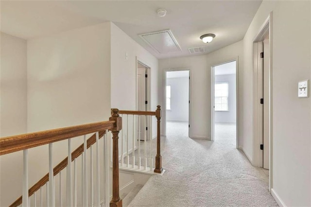 corridor with visible vents, an upstairs landing, light carpet, baseboards, and attic access