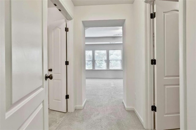 hallway featuring light carpet and baseboards