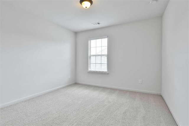 unfurnished room with visible vents, light carpet, and baseboards