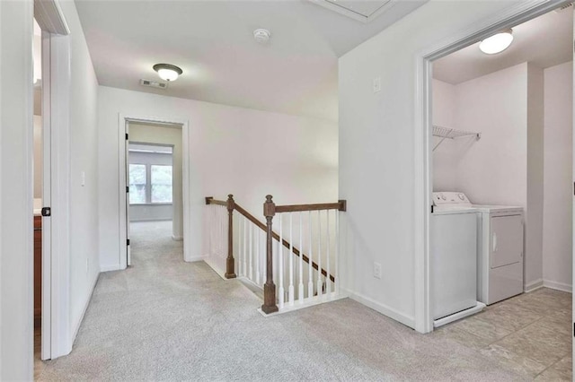 hall featuring an upstairs landing, visible vents, light colored carpet, and separate washer and dryer