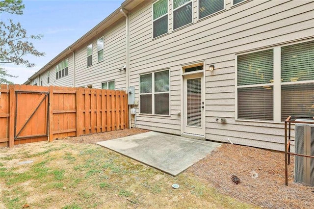 rear view of property with a patio area, central AC unit, a gate, and fence