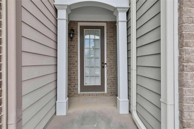 view of exterior entry featuring brick siding and a porch