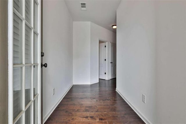 corridor featuring visible vents, dark wood-type flooring, and baseboards