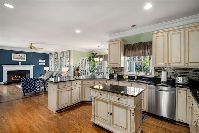 kitchen featuring decorative light fixtures, stainless steel dishwasher, open floor plan, a kitchen island, and a sink