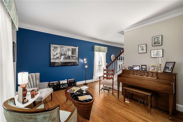 sitting room with baseboards, crown molding, stairway, and wood finished floors