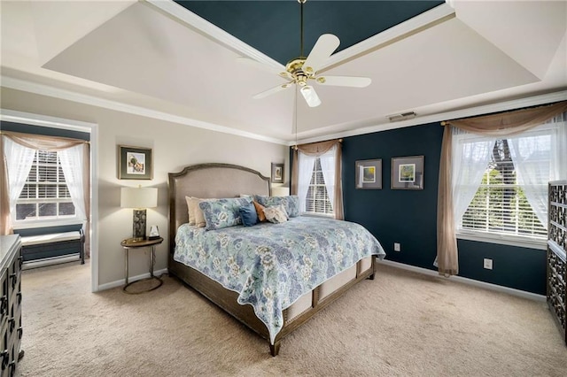 carpeted bedroom with baseboards, visible vents, a tray ceiling, and ceiling fan