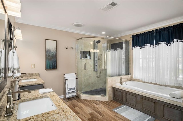 full bathroom with crown molding, visible vents, a sink, and wood finished floors