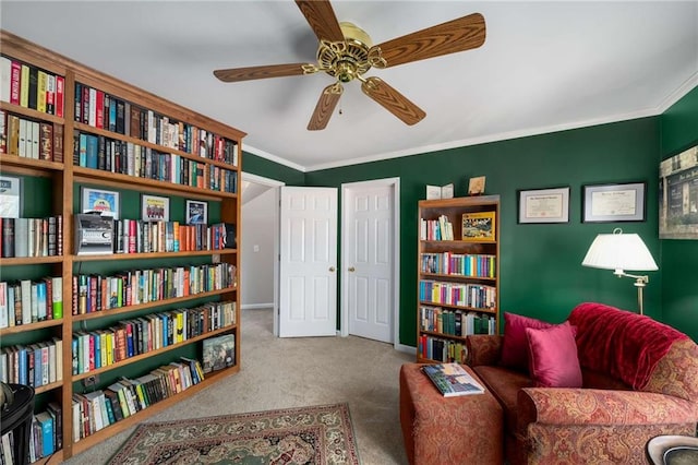 sitting room with ornamental molding, light carpet, baseboards, and a ceiling fan