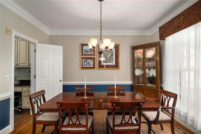 dining area featuring visible vents, crown molding, an inviting chandelier, and wood finished floors