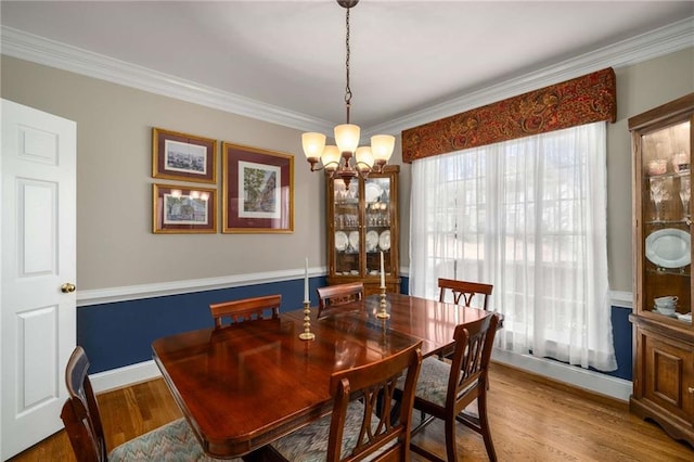 dining room featuring ornamental molding, baseboards, an inviting chandelier, and wood finished floors