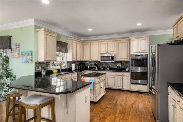 kitchen with a breakfast bar area, stainless steel appliances, tasteful backsplash, a sink, and a kitchen island