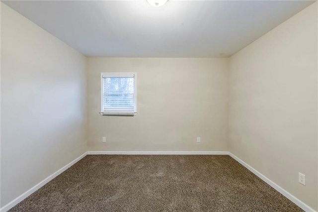 unfurnished room featuring dark carpet and baseboards