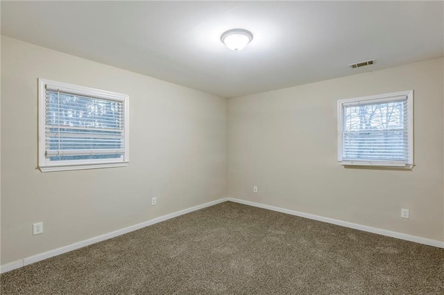 spare room with carpet, visible vents, and baseboards