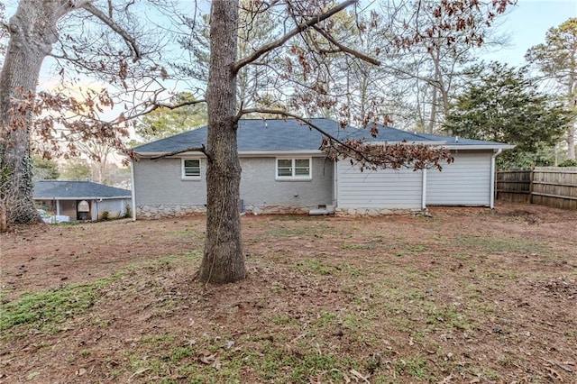 rear view of house with crawl space, fence, and brick siding