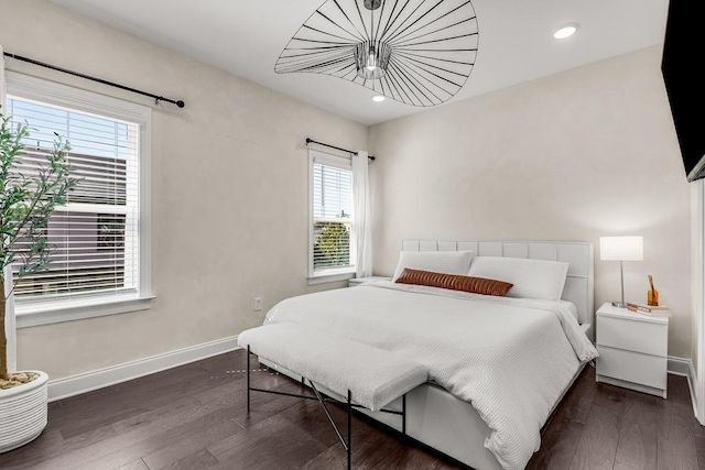 bedroom with dark hardwood / wood-style floors and multiple windows