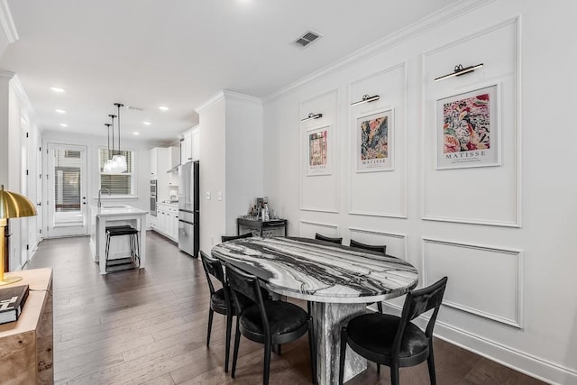 dining room with dark hardwood / wood-style floors, ornamental molding, and sink