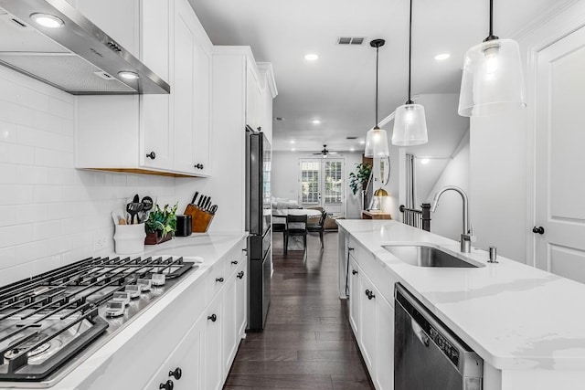 kitchen with white cabinetry, an island with sink, wall chimney exhaust hood, stainless steel appliances, and decorative light fixtures