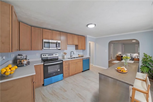 kitchen with a kitchen breakfast bar, sink, ornamental molding, and stainless steel appliances