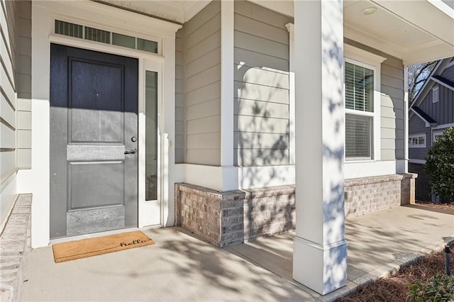 entrance to property with a porch and brick siding