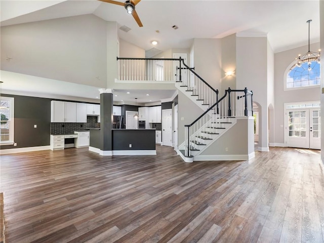 11405 Donnington Dr, Duluth, GA 30097 - unfurnished living room featuring stairway, a high ceiling, a ceiling fan, dark wood-style flooring, and a chandelier
