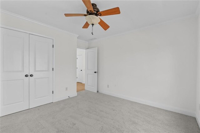 unfurnished bedroom featuring ceiling fan, baseboards, a closet, ornamental molding, and carpet flooring