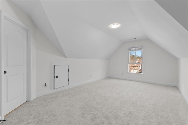 bonus room with baseboards, vaulted ceiling, and light carpet