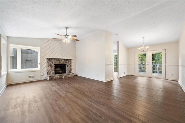 unfurnished living room with ceiling fan with notable chandelier, a fireplace, a textured ceiling, dark hardwood / wood-style flooring, and vaulted ceiling