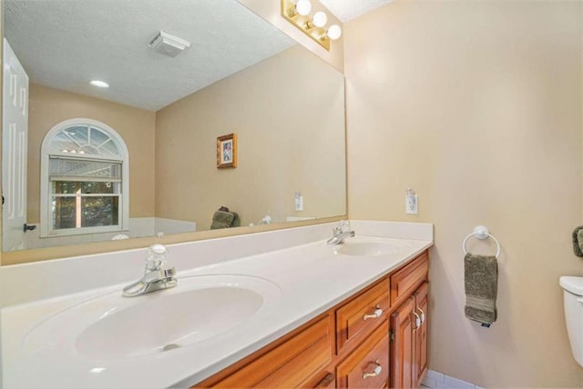 bathroom with a textured ceiling, vanity, and toilet