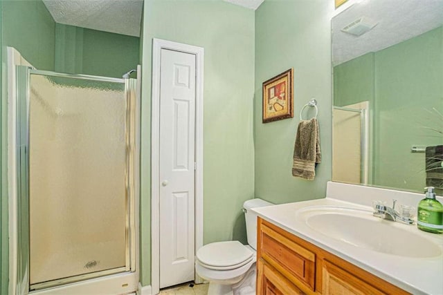 bathroom featuring toilet, vanity, a textured ceiling, and a shower with shower door