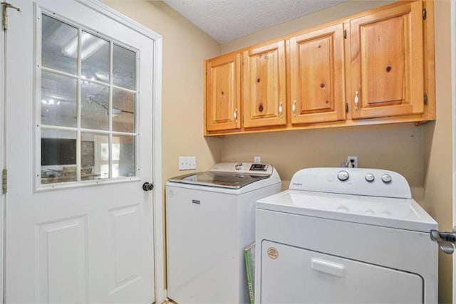 laundry area with a textured ceiling, separate washer and dryer, and cabinets