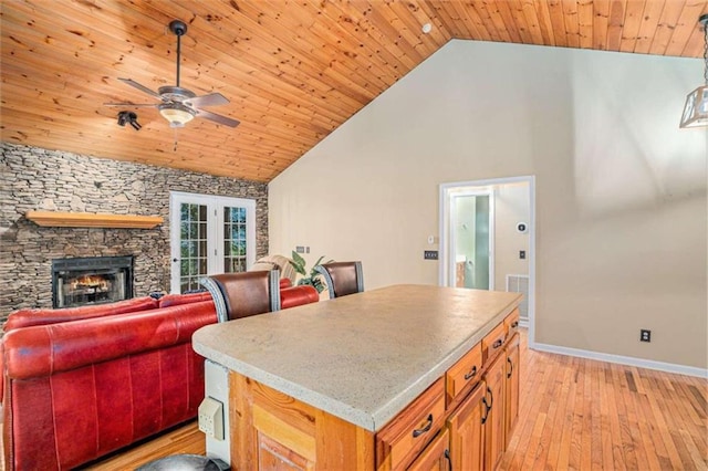 kitchen featuring a kitchen island, wooden ceiling, a fireplace, and ceiling fan