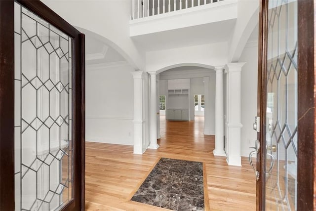 entrance foyer with ornate columns, ornamental molding, and hardwood / wood-style flooring