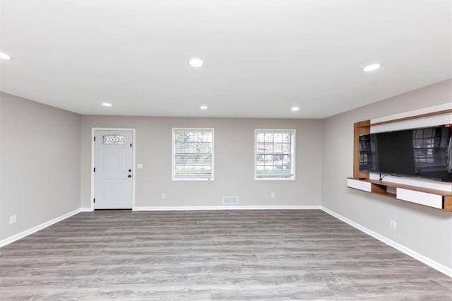 unfurnished living room featuring visible vents, recessed lighting, wood finished floors, and baseboards
